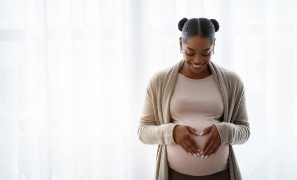 Pregnant woman smiling with hands on belly